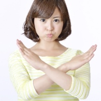 腕で×を作る女性